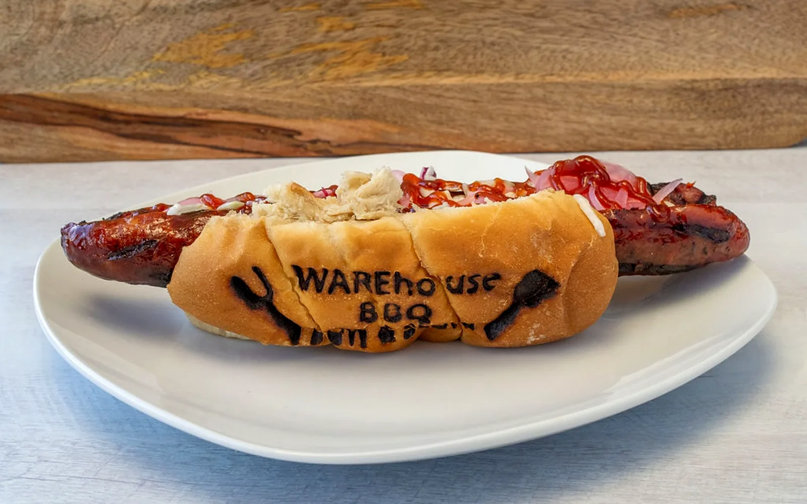 Andouille sausage sandwich on a bun branded with the Warehouse BBQ name